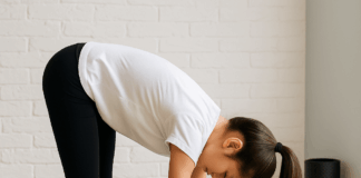Teen girl doing a forward fold stretch on a yoga mat before the SAT exam